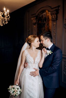 Genç bir çift karanlık bir stüdyoda, bir ayna ve bir avizeyle.