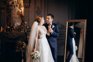 Genç bir çift karanlık bir stüdyoda, bir ayna ve bir avizeyle.