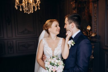 Genç bir çift karanlık bir stüdyoda, bir ayna ve bir avizeyle.