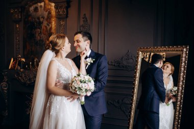 Genç bir çift karanlık bir stüdyoda, bir ayna ve bir avizeyle.