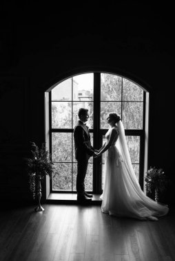 Genç bir çift karanlık bir stüdyoda, bir ayna ve bir avizeyle.