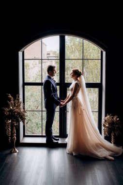 Genç bir çift karanlık bir stüdyoda, bir ayna ve bir avizeyle.