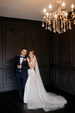 Genç bir çift karanlık bir stüdyoda, bir ayna ve bir avizeyle.