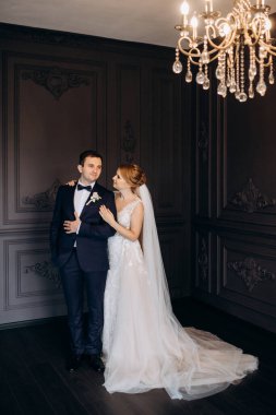 Genç bir çift karanlık bir stüdyoda, bir ayna ve bir avizeyle.