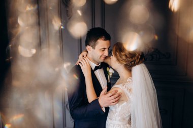 Genç bir çift karanlık bir stüdyoda, bir ayna ve bir avizeyle.