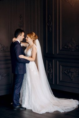 Genç bir çift karanlık bir stüdyoda, bir ayna ve bir avizeyle.