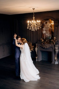 Genç bir çift karanlık bir stüdyoda, bir ayna ve bir avizeyle.