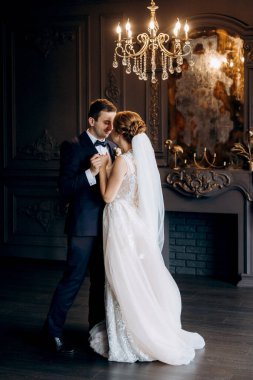 Genç bir çift karanlık bir stüdyoda, bir ayna ve bir avizeyle.