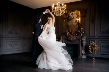 Genç bir çift karanlık bir stüdyoda, bir ayna ve bir avizeyle.