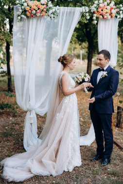 Bir adamla bir kızın düğün seremonisi Orman yolunda bir kemerin arka planına karşı