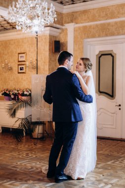 Gelin ve damadın ilk düğün dansı gün batımında restoranın içinde.