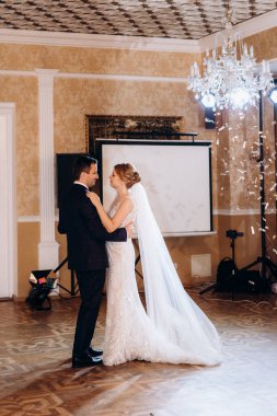 Gelin ve damadın ilk düğün dansı gün batımında restoranın içinde.