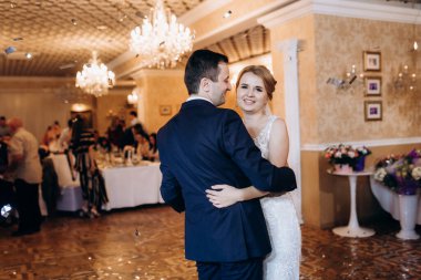 Gelin ve damadın ilk düğün dansı gün batımında restoranın içinde.