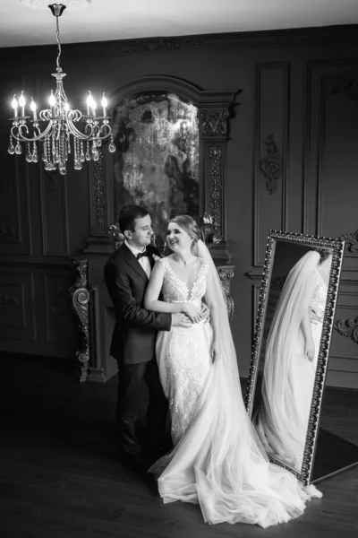 Genç bir çift karanlık bir stüdyoda, bir ayna ve bir avizeyle.