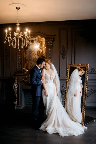 Genç bir çift karanlık bir stüdyoda, bir ayna ve bir avizeyle.