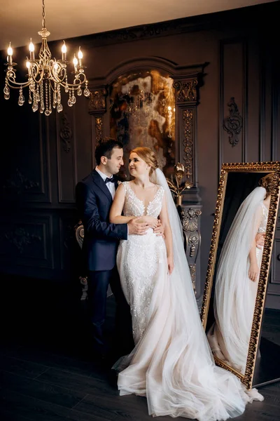 Genç bir çift karanlık bir stüdyoda, bir ayna ve bir avizeyle.