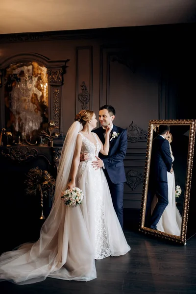 Genç bir çift karanlık bir stüdyoda, bir ayna ve bir avizeyle.