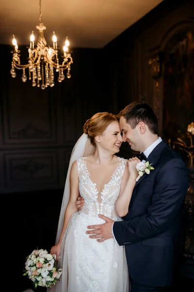 Genç bir çift karanlık bir stüdyoda, bir ayna ve bir avizeyle.