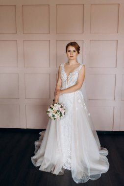 Gelin lavanta renkli pofuduk gelinlik içinde parlak bir stüdyoda buketle