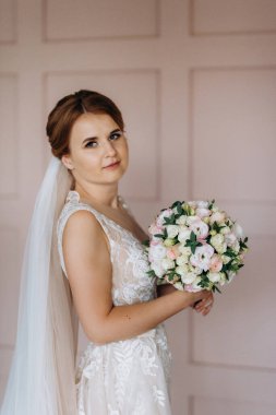 Gelin lavanta renkli pofuduk gelinlik içinde parlak bir stüdyoda buketle