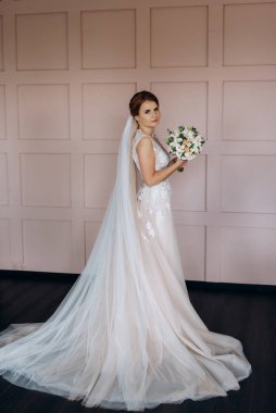 Gelin lavanta renkli pofuduk gelinlik içinde parlak bir stüdyoda buketle