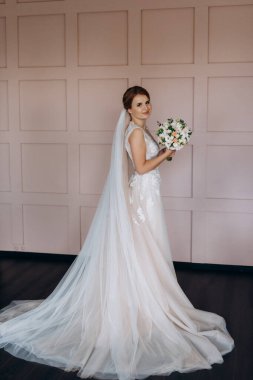 Gelin lavanta renkli pofuduk gelinlik içinde parlak bir stüdyoda buketle