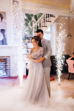 the first dance of the bride and groom inside a restaurant with heavy smoke