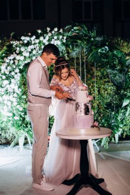 newlyweds happily cut, laugh and taste the wedding cake