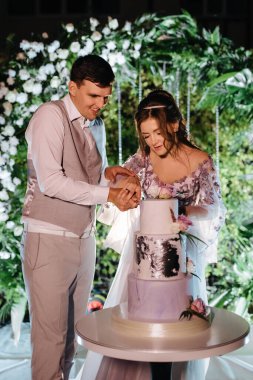 newlyweds happily cut, laugh and taste the wedding cake