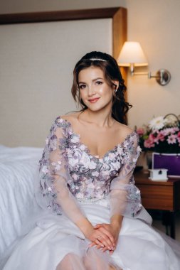 Sabahleyin bir otelde lavantalı gelinlik giymiş bir gelinin portresi.