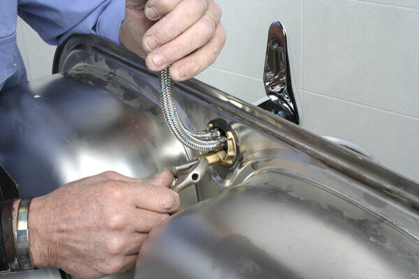 Construction worker installing a faucet on a kitchen sink.