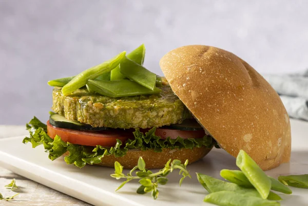 Yeşil fasulye ve nohuttan yapılmış vejetaryen hamburger, domates, salatalık ve marulla servis edilir..