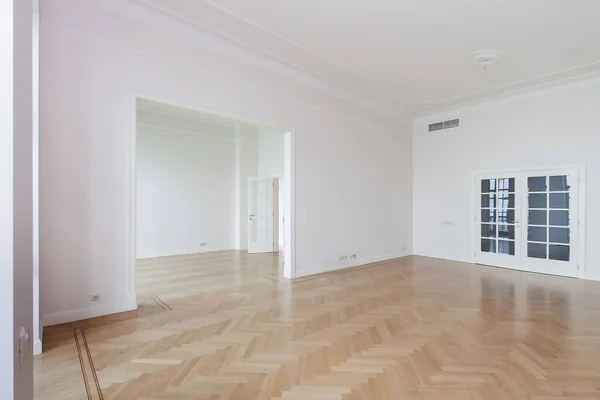 Пустая комната с побеленным плавающим ламинатом и недавно окрашенной белой стеной на заднем плане — стоковое фото