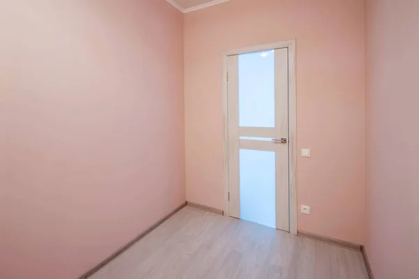 Порожня маленька кімната з побіленими ламінованими підлогами і пофарбованою рожевою стіною на фоні — стокове фото