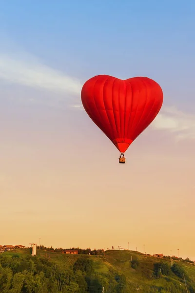 Herz fliegt roter Heißluftballon in den Abendhimmel. — Stockfoto