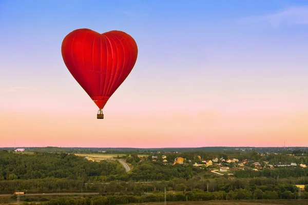 Heart flying red hot air balloon in sunset blue pink sky with a