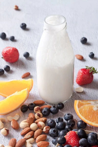 Fermented drink kefir bottle and nuts, berries, citrus fruits with immune boosting properties white background — Stock Photo, Image