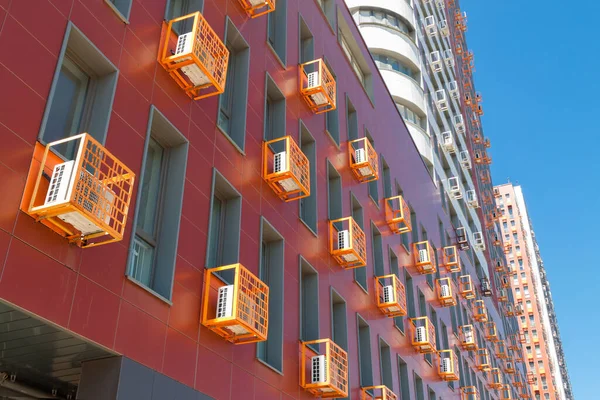 Pared de fachada de edificio naranja corporativa con muchos acondicionadores de aire sobre fondo de cielo azul —  Fotos de Stock