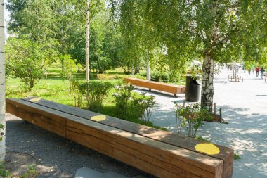 Ahşap bankta sarı etiket. Şehir parkında alternatif koltuklar. Daha fazla vites kovid 19 riskini azaltmak için. Uygulamada güvenlik toplumsal mesafeyi ölçüyor.