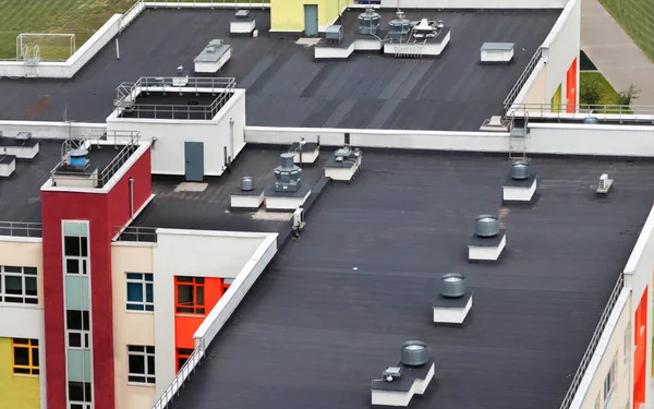 Yeşil futbol sahası yaz günü modern bir apartmanın tepesinde, klimalı ve su yalıtım zarlarıyla en üstteki düz çatı..
