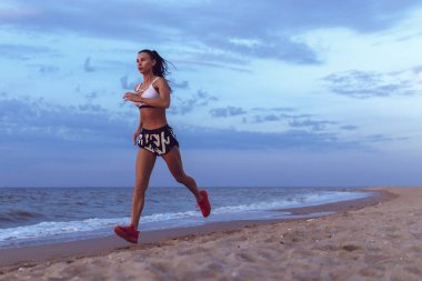 sağlıklı genç fitness kadın iz runner gündoğumu sahil üzerinde çalışan