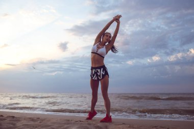 kız spor sabah erken sahil üzerinde yapmadan önce bir ısınma yok. Bir kuru ile atletik yapılı bir kız kas kütlesi.