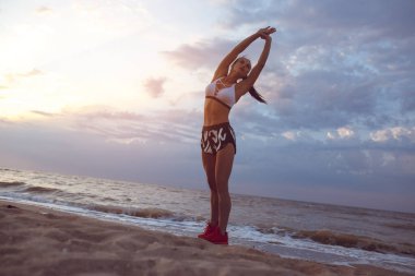 kız spor sabah erken sahil üzerinde yapmadan önce bir ısınma yok. Bir kuru ile atletik yapılı bir kız kas kütlesi.