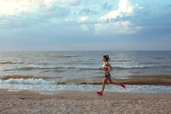 健康青年健身女人径赛跑者在日出海边上运行 — 图库照片