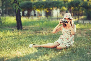 küçük kız parkta çim üzerinde oturan fotoğraf makinesi tarafından oynanır. Selfie yapıyor ve dünya çapında Fotoğrafçılık