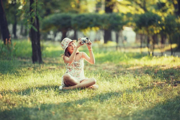 Küçük Kız Parkta Çim Üzerinde Oturan Fotoğraf Makinesi Tarafından Oynanır — Stok fotoğraf