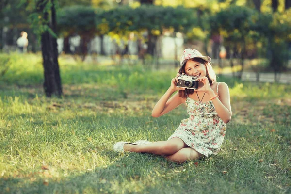 Κοριτσάκι Παίζεται Από Φωτογραφική Μηχανή Φωτογραφιών Που Κάθεται Στο Γρασίδι — Φωτογραφία Αρχείου