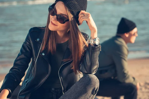 Junges verliebtes Paar spaziert am Meer entlang. Frühling, Herbst. Der Typ trägt Jacke und Hut. Mädchen mit Hut und Lederjacke mit Schal — Stockfoto