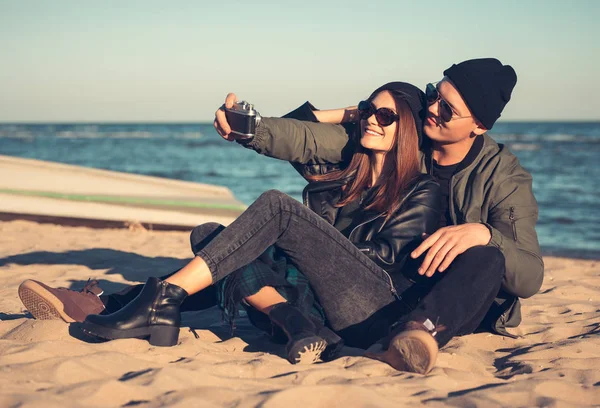 Ein junges Liebespaar verbringt viel Zeit am Meer und macht Selfies. Mann und Frau haben Frühlingskleidung — Stockfoto