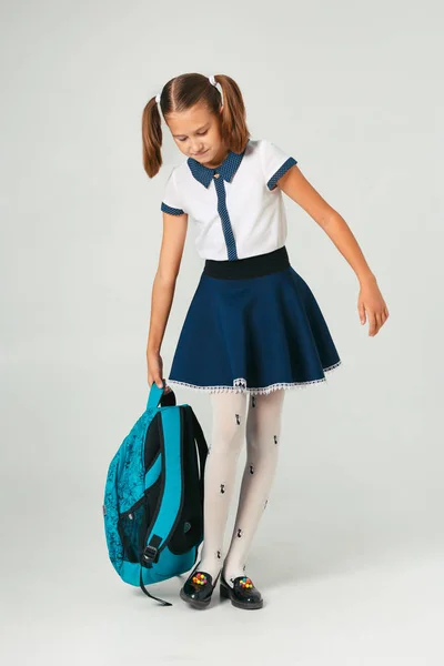 Schülerin in Schuluniform mit schwerem Rucksack. das Problem der Gewichtung studentischer Accessoires — Stockfoto